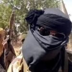 Armed bandits carrying weapons in a rural area, symbolising Nigeria's ongoing security challenges amid rising government security expenditure.