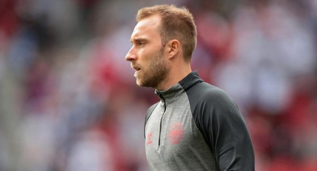 Christian Eriksen lying on the pitch during Denmark vs Ukraine friendly as medical staff and teammates surround him while treatment is administered and play is halted.