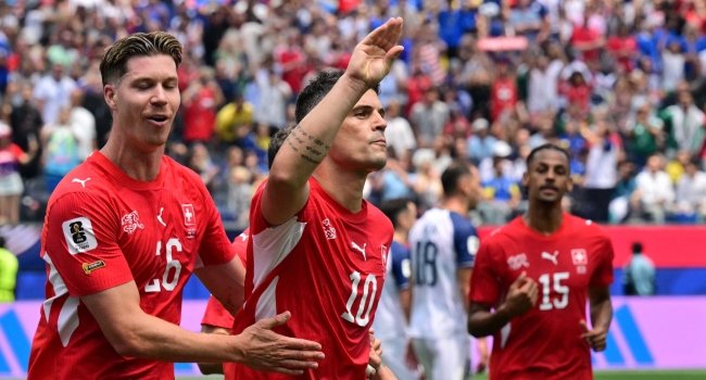 Switzerland players celebrating during a 4-1 World Cup Group B victory over Bosnia and Herzegovina at SoFi Stadium, with Granit Xhaka involved in the match action.