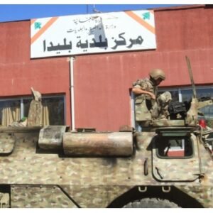 Lebanese soldier sits atop a military vehicle outside a municipal building in Blida, southern Lebanon, following clashes amid the Israel-Hezbollah conflict and ceasefire announcement.