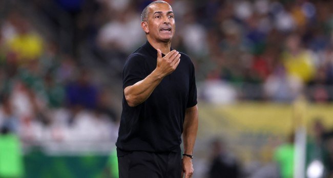 Tunisia head coach Sabri Lamouchi on the touchline during World Cup match action against Sweden, with players reacting after defeat.