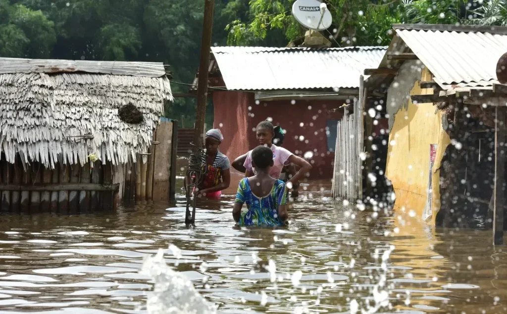 Flooded street in Abidjan with submerged vehicles and rising floodwaters after heavy rainfall in Côte d’Ivoire.