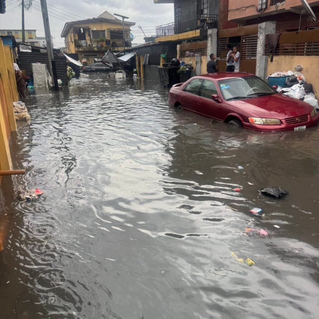 Floodwaters covering residential streets in Lagos as residents wade through flooded roads following heavy rainfall.