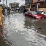 Floodwaters covering residential streets in Lagos as residents wade through flooded roads following heavy rainfall.