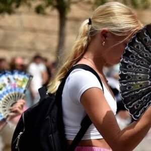 A women use hand fans to fans themselves through intense heat during a heatwave in Evora, Portugal.
