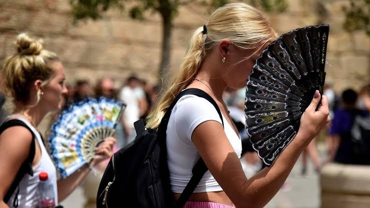 A women use hand fans to fans themselves through intense heat during a heatwave in Evora, Portugal.