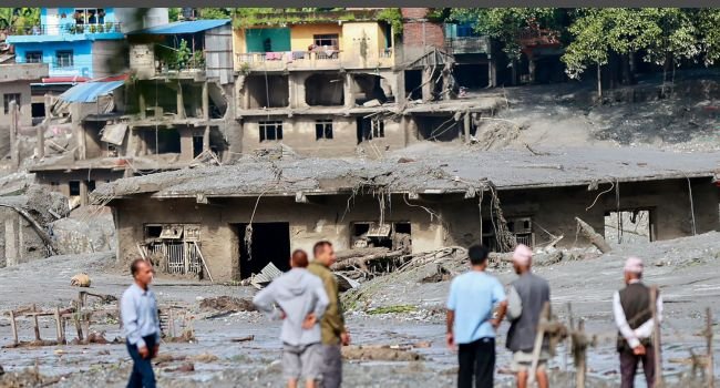 Rescue workers inspect mud-covered homes after deadly flash floods and a glacial collapse in Nepal's Nuwakot district.