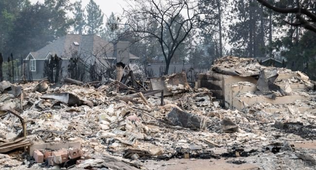 Firefighters inspect burned homes in Spokane, Washington, after fast-moving wildfires destroyed hundreds of properties and forced mass evacuations.