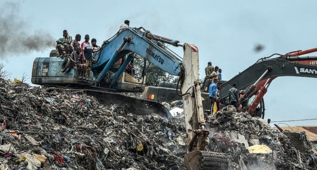 Rescue workers use excavators to search through a collapsed landfill in Conakry, Guinea, after a deadly rubbish mound collapse.