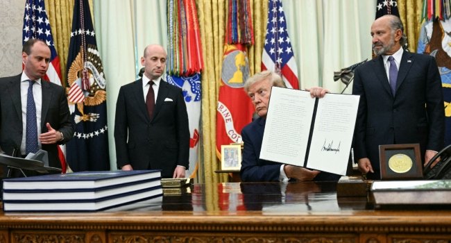 US President Donald Trump holds up a newly signed executive order in the Oval Office after announcing new restrictions on birthright citizenship.