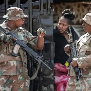 Police and residents gather near the scene of a deadly bar shooting in Wedela, South Africa.