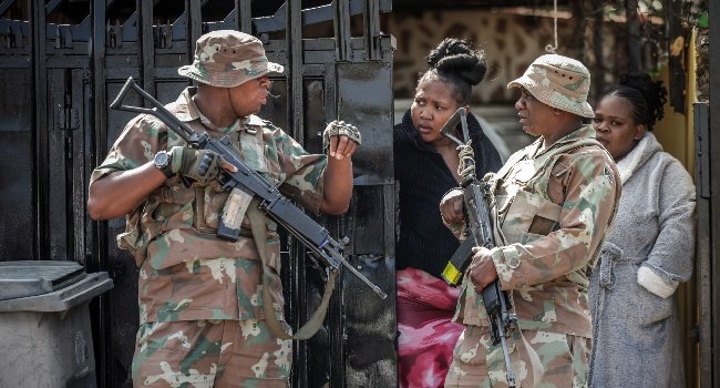 Police and residents gather near the scene of a deadly bar shooting in Wedela, South Africa.