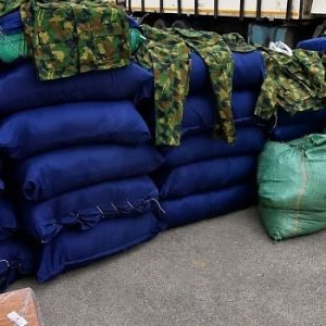 Police officers display 47 sacks of intercepted military camouflage uniforms and cartons of suspected illicit substances seized during an operation in Lagos.