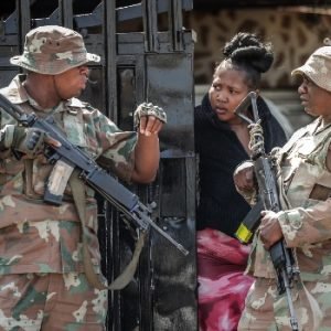 Police and residents gather near the scene of a deadly bar shooting in Wedela, South Africa.