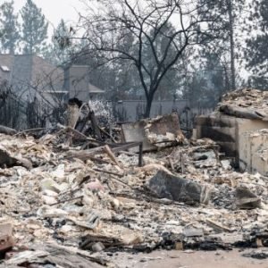 Firefighters inspect burned homes in Spokane, Washington, after fast-moving wildfires destroyed hundreds of properties and forced mass evacuations.
