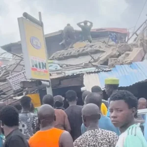 Rescue workers and residents gather around the rubble of a collapsed three-storey building in the Alakija area of Lagos as several people are feared trapped beneath the debris.