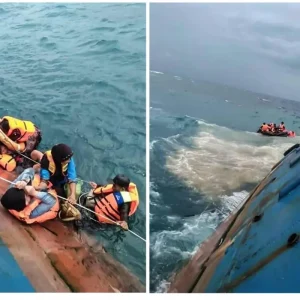 Overturned Indonesian ferry floating in rough waters during a search-and-rescue operation in the Java Sea.