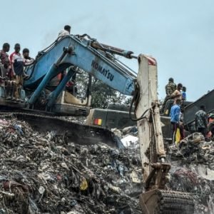 Rescue workers use excavators to search through a collapsed landfill in Conakry, Guinea, after a deadly rubbish mound collapse.