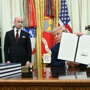 US President Donald Trump holds up a newly signed executive order in the Oval Office after announcing new restrictions on birthright citizenship.